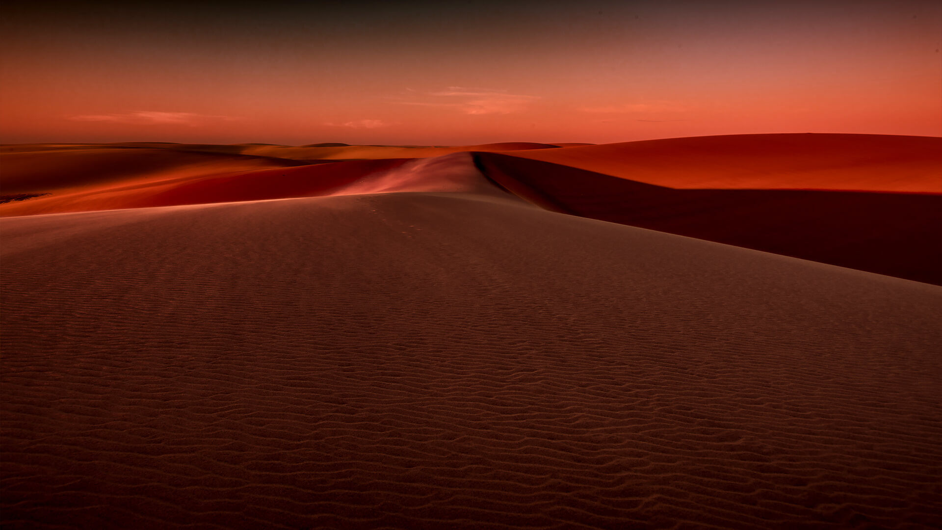 Textura das dunas ao entardecer, com um céu degradê de tons quentes.