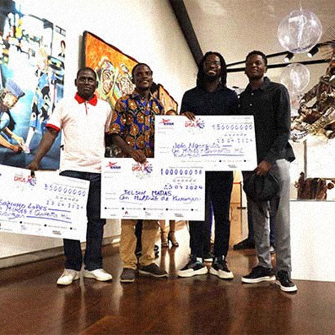 Grupo de artistas angolanos recebendo prémios com cheques simbólicos durante cerimónia cultural.